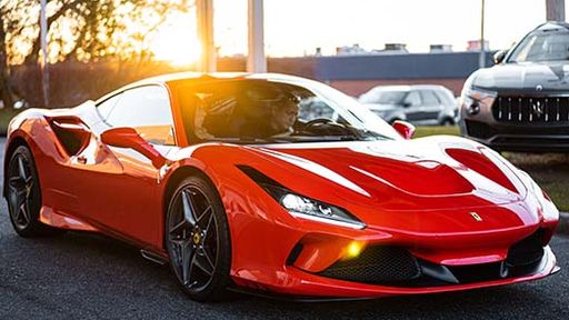 A red Ferrari sports car parked by the street at sunset